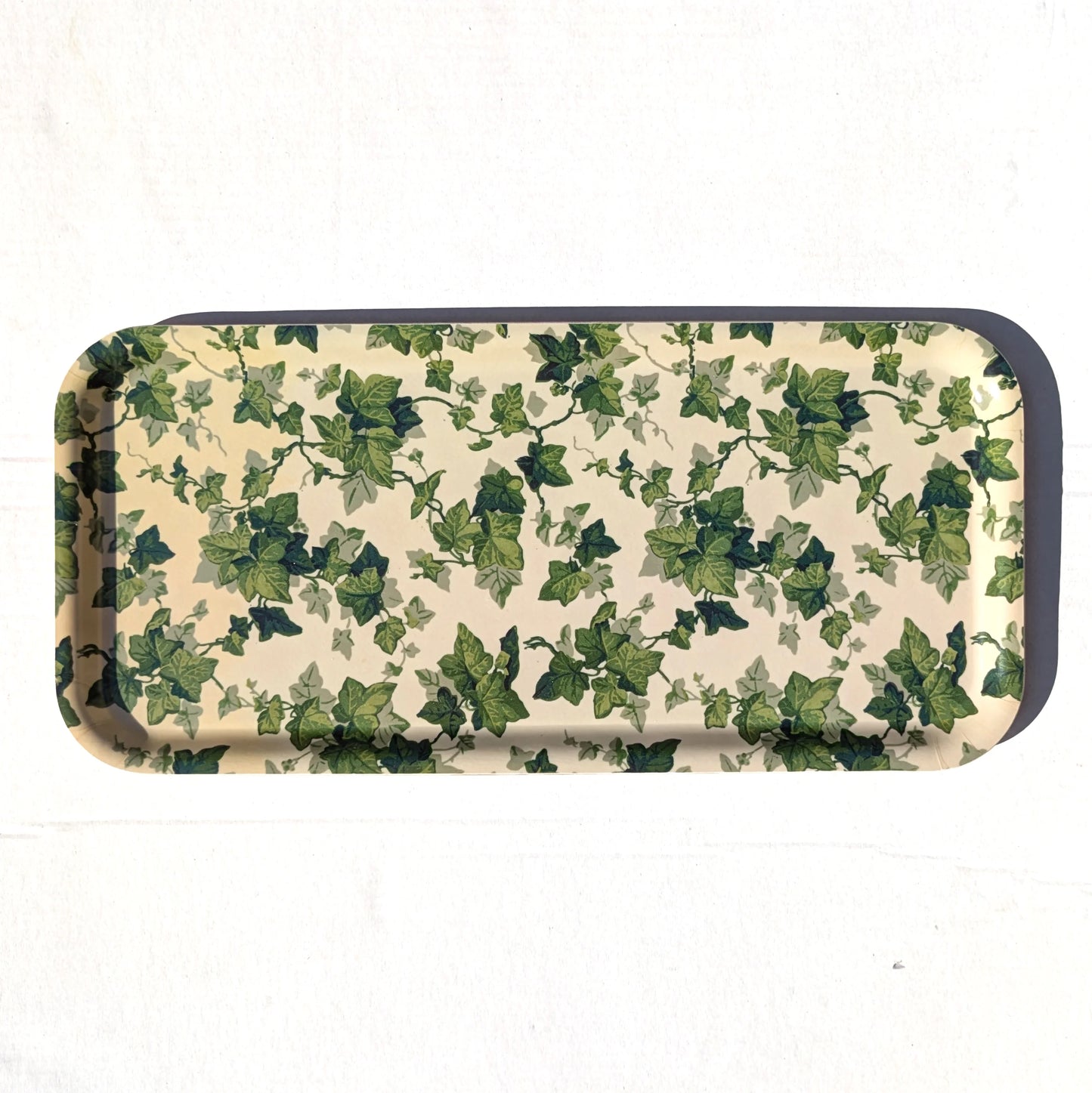 A rectangular metal tray with rounded corners, featuring an all-over green ivy leaf pattern on a cream-colored background, with a dark metallic rim.
