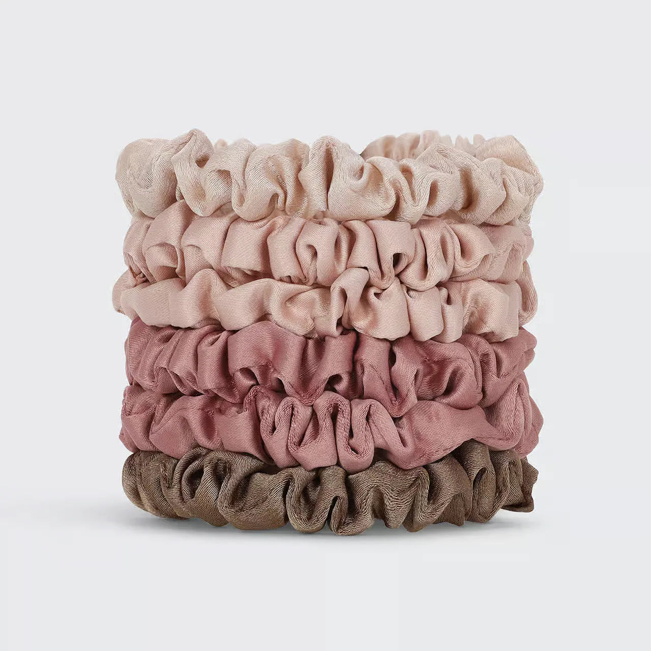 Stack of pink and brown scrunchies on a light gray background