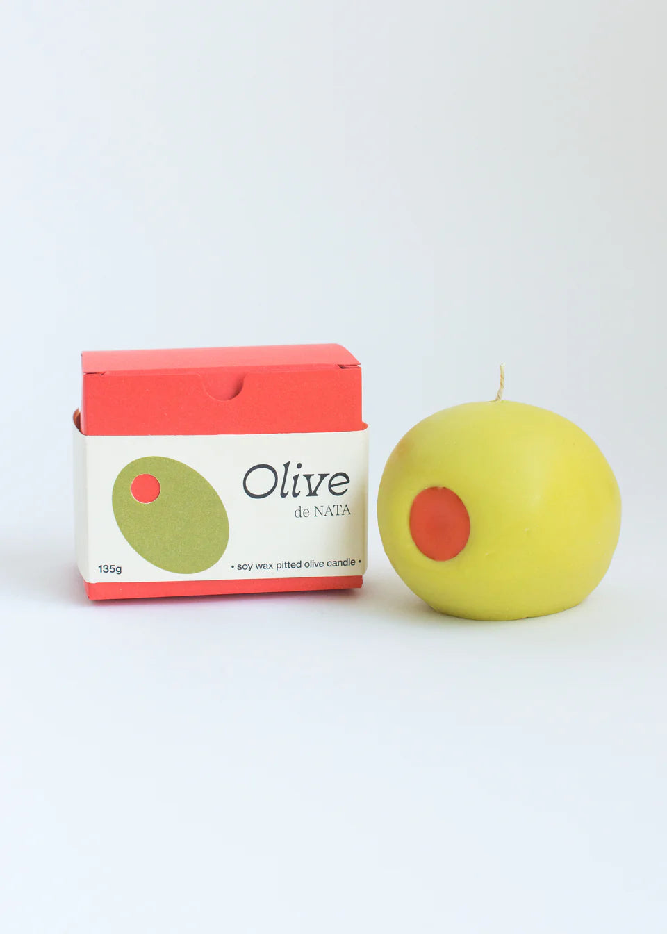 Green candle with red center next to a box labeled 'Olive de Nata' on a white background