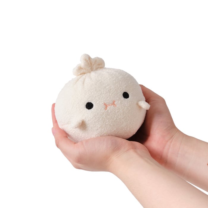 Small plush toy resembling a bun held in a hand against a white background