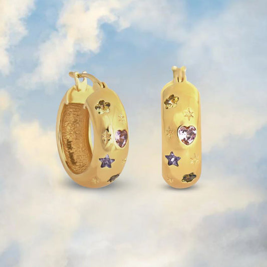 Chunky gold hoop earrings studded with pastel coloured gemstones on a cloudy sky background