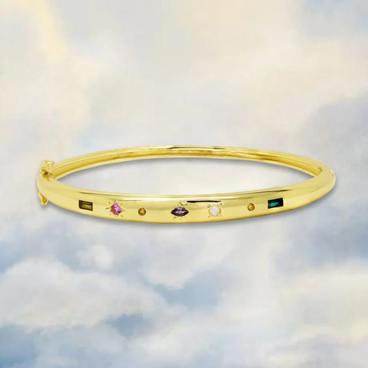 gold bangle with colourful gemstones on a clousy sky background 
