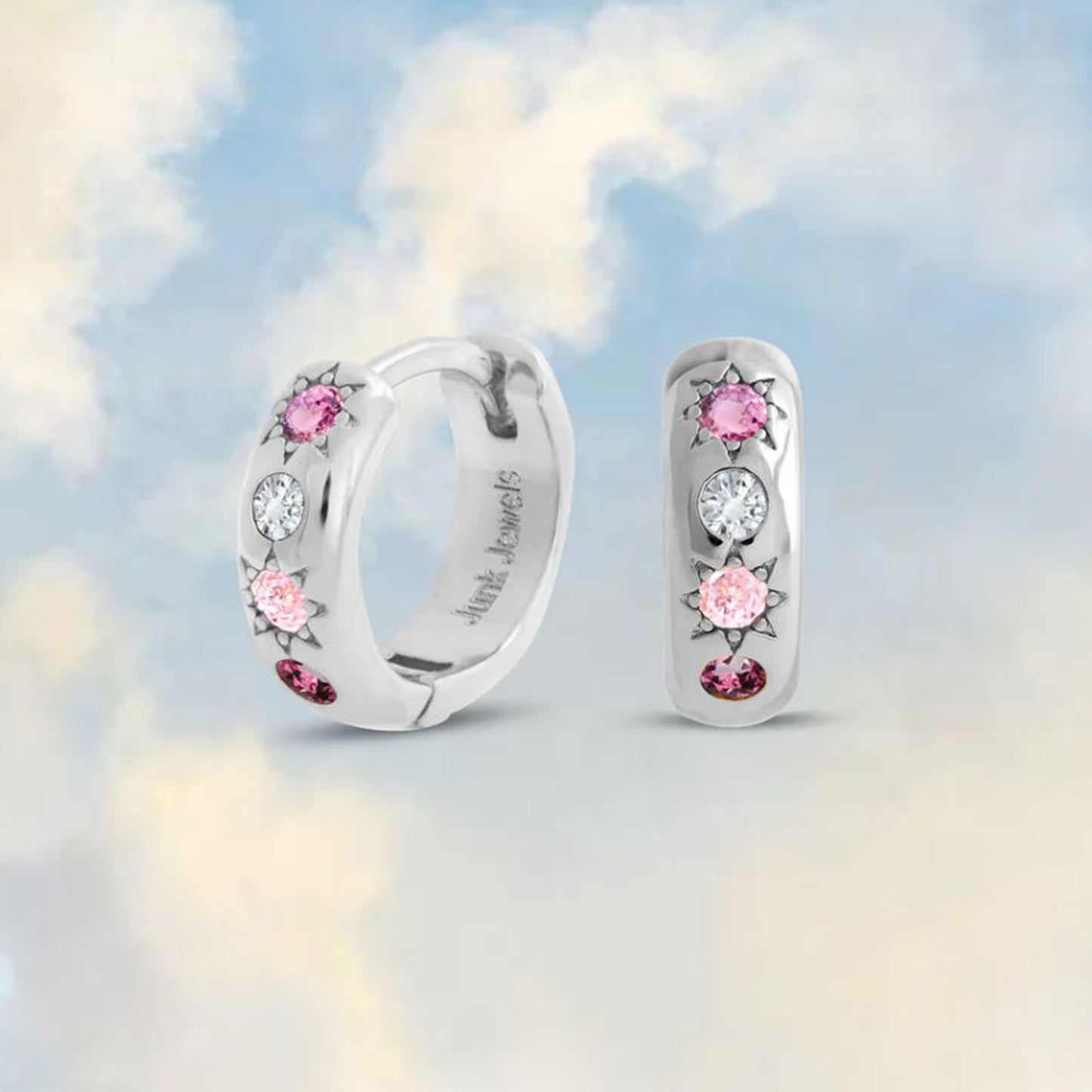 silver huggie hoops with pink gemstones on a cloudy sky background 