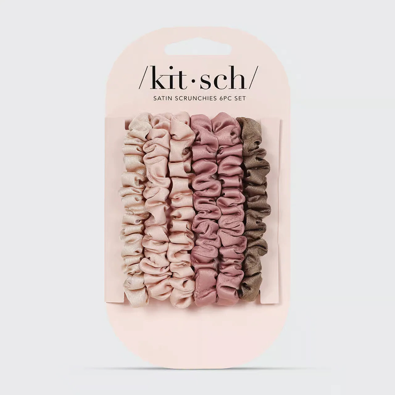 Set of satin scrunchies in pink and beige packaging with 'kit-sch' branding on a light gray background