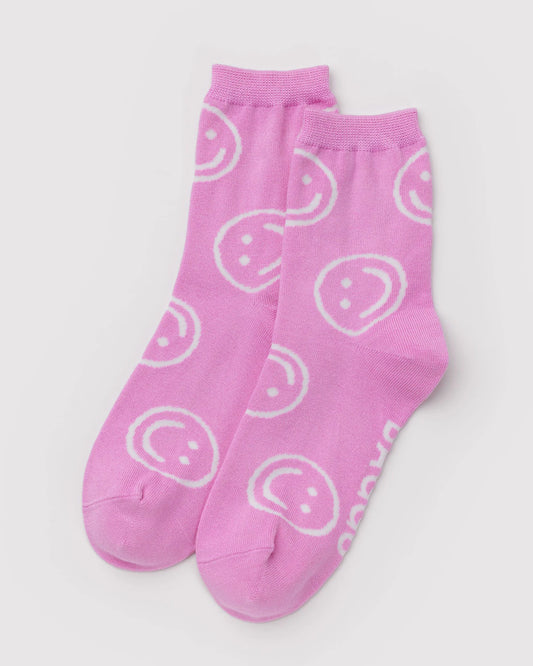 Pink socks with white smiley face patterns on a light gray background