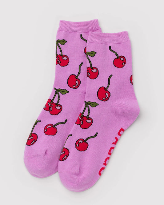 Pink socks with red cherry pattern on a light gray background