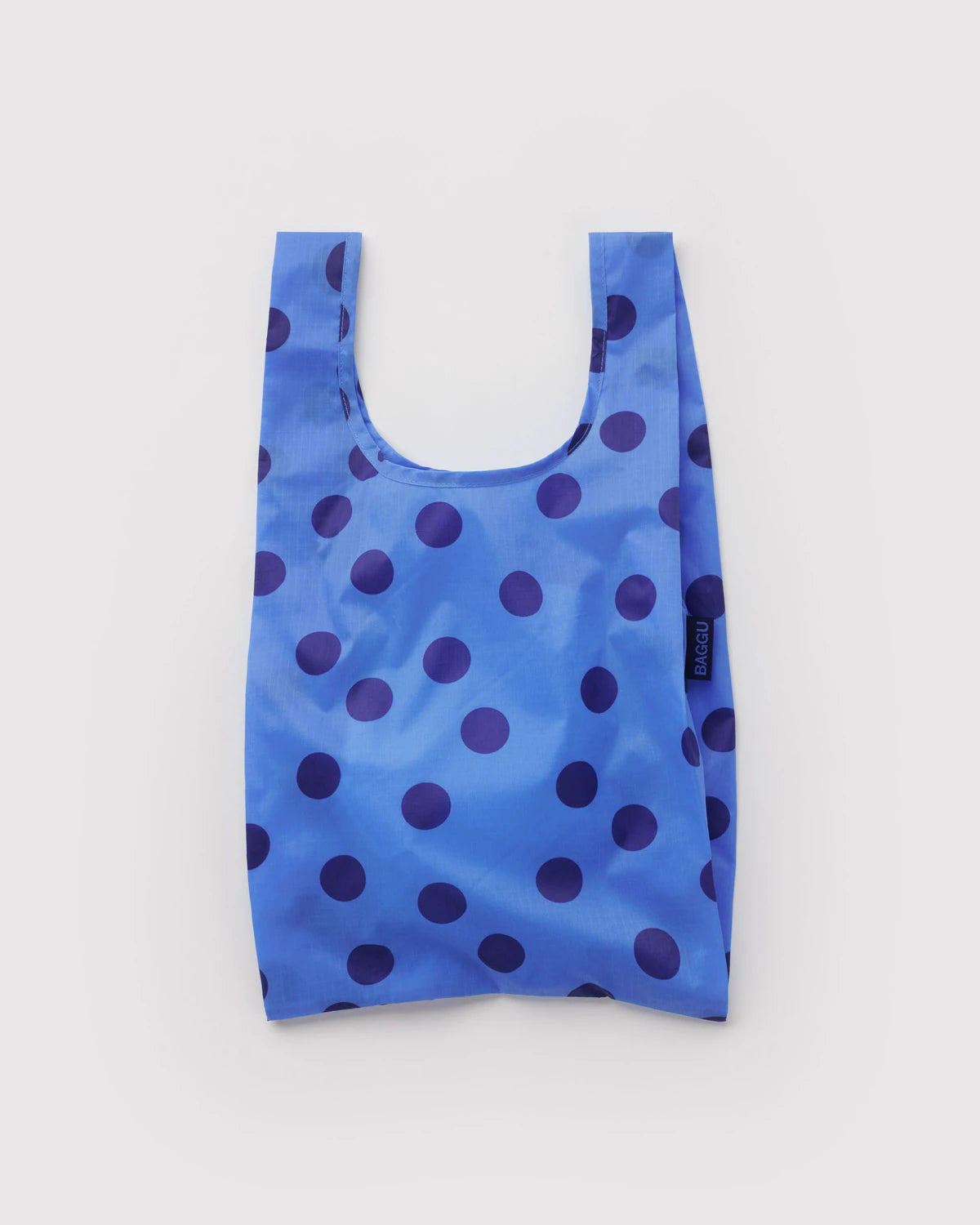 Blue reusable shopping bag with navy polka dots on a light gray background