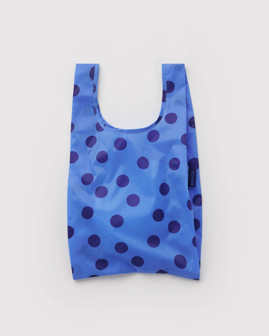 Blue reusable shopping bag with navy polka dots on a light gray background