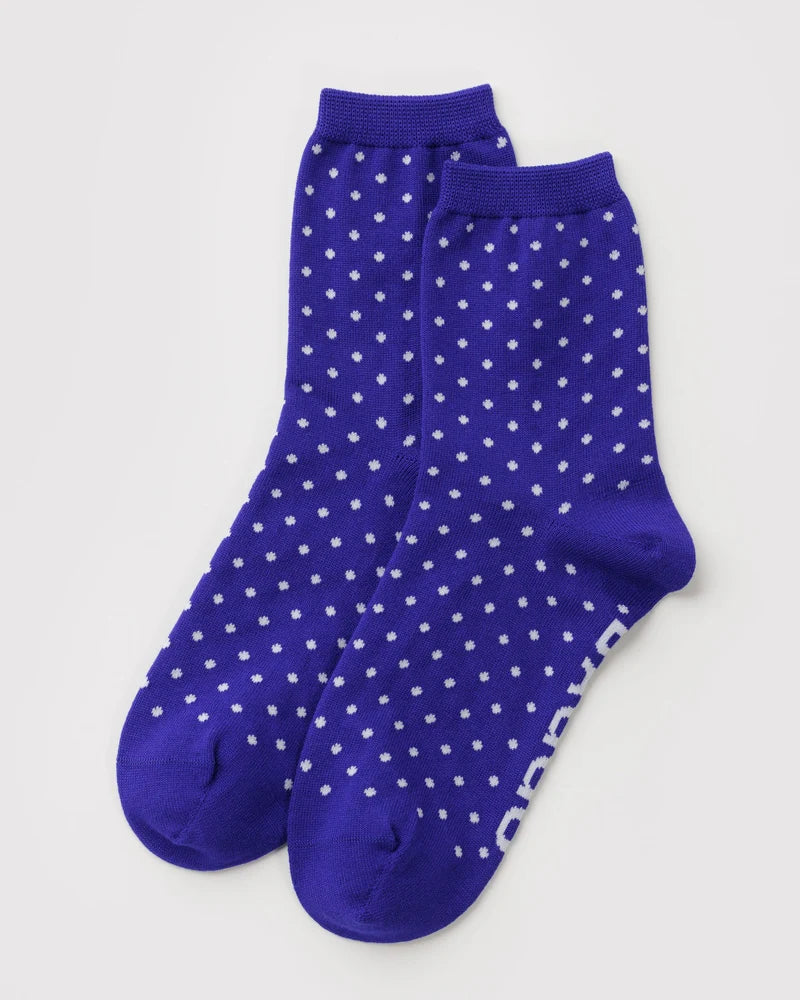 Pair of blue socks with white polka dots on a light gray background