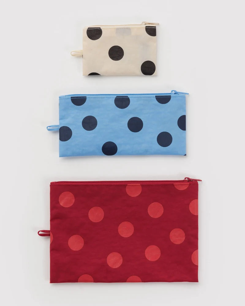 Three polka dot pouches in beige, blue, and red on a white background