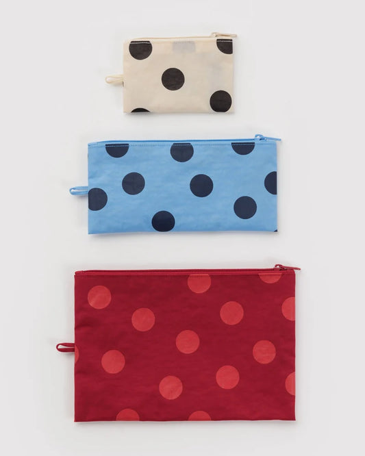 Three polka dot pouches in beige, blue, and red on a white background