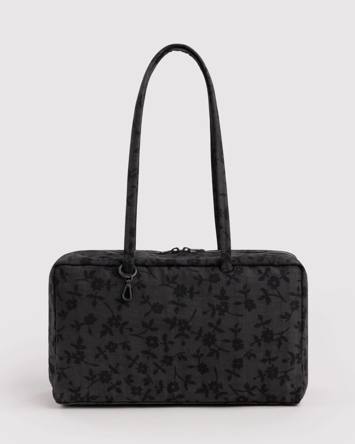 A black rectangular handbag with a subtle tonal floral pattern, featuring two long shoulder straps and a top zipper closure, set against a plain light gray background.