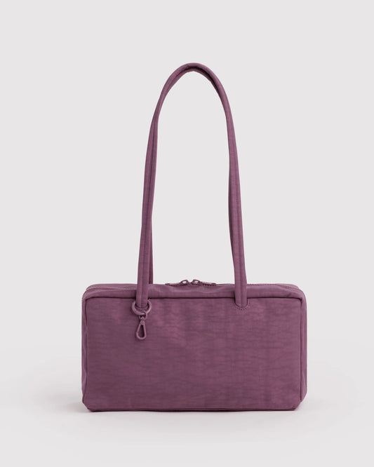 A rectangular purple shoulder bag with a textured fabric exterior, dual top handles, and a small hanging ring detail, shown against a plain light gray background.