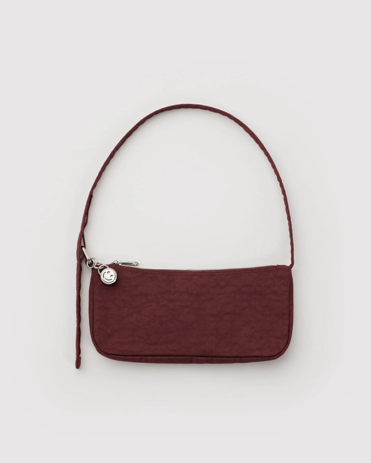Maroon handbag with a strap on a light gray background