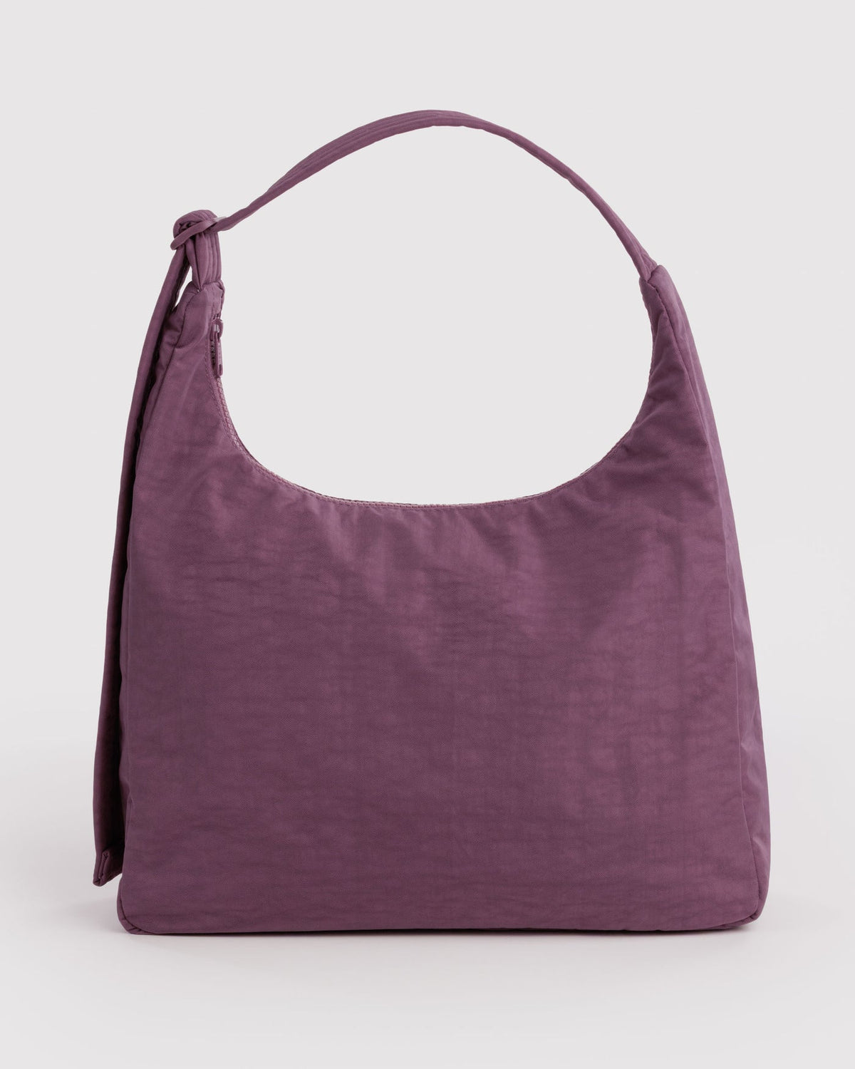A dusty purple slouchy shoulder bag made of textured crinkled fabric, featuring a single shoulder strap and a side tie detail, photographed on a light gray studio background.