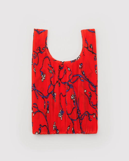Red pleated bag with black floral pattern on a light gray background