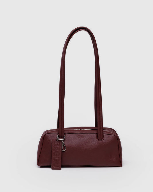 Burgundy handbag with a strap on a light gray background