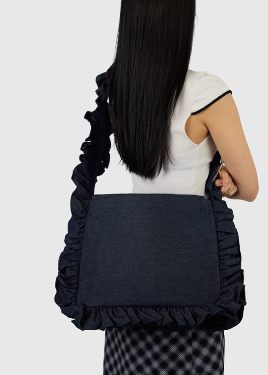 Person wearing a navy blue ruffled bag on a white background