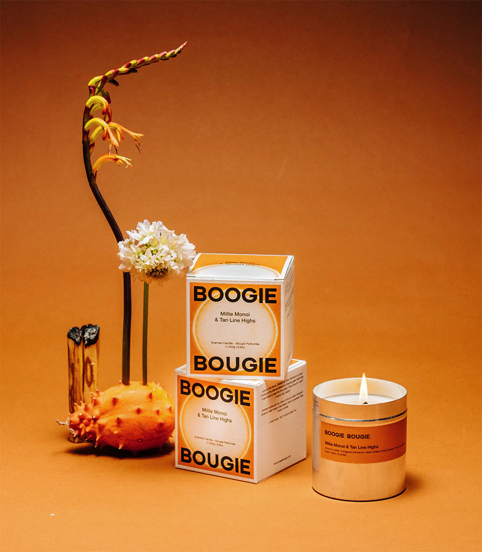 Boogie Bougie Millie Monoi  & Tan Line Highs Candle on a orange background 