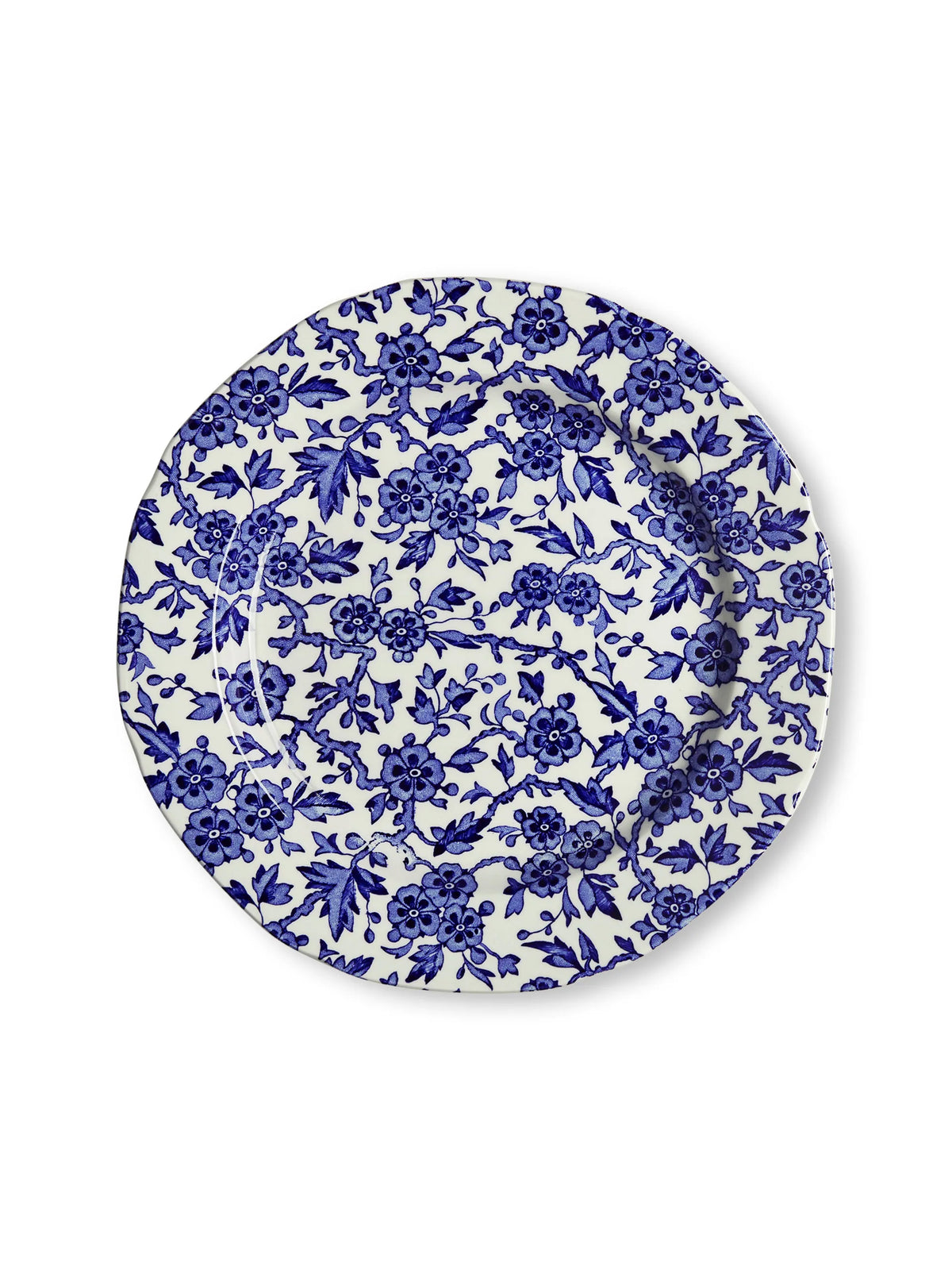 A round ceramic plate featuring an intricate blue floral and botanical pattern on a white background, photographed from directly above on a clean white surface.