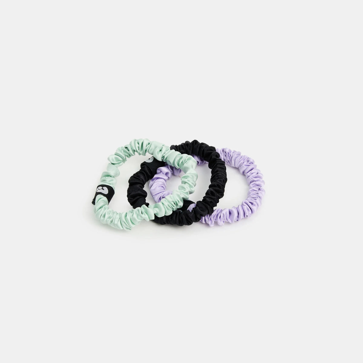 Set of three scrunchies in green, black, and purple on a white background