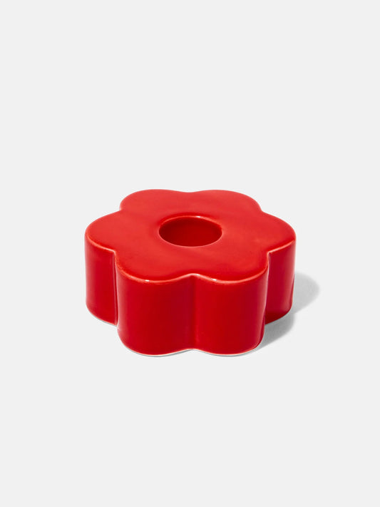 Red flower-shaped candle holder on a white background