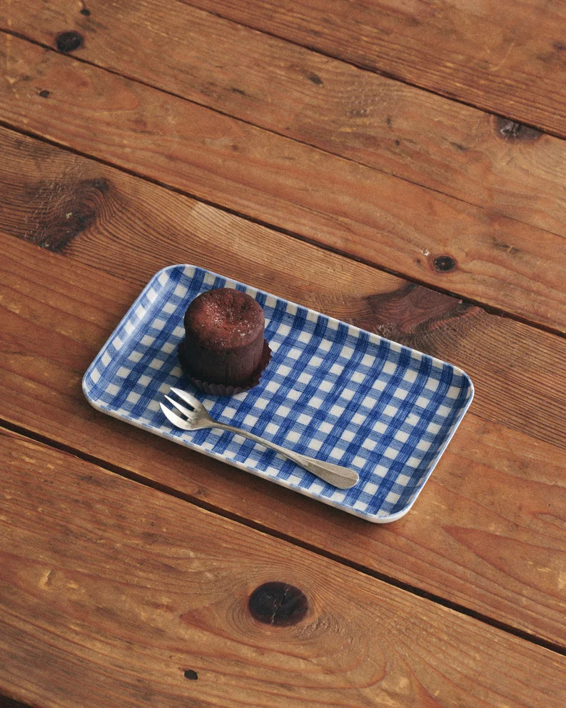 Blue checkered tray with a dessert and spoon on a wooden surface