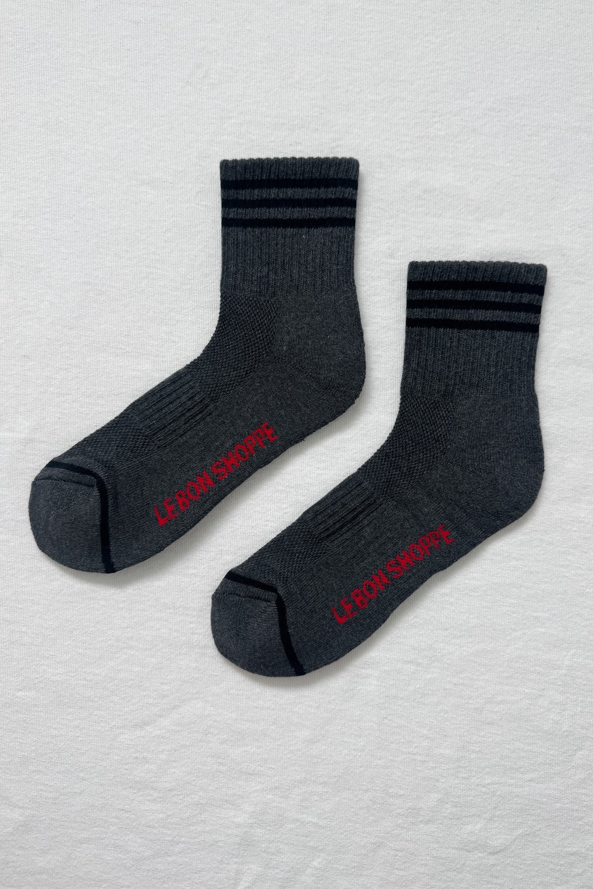 Two dark gray socks with red text on a light gray textured background