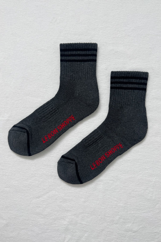 Two dark gray socks with red text on a light gray textured background