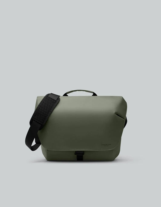 Green bag with a black strap on a light gray background