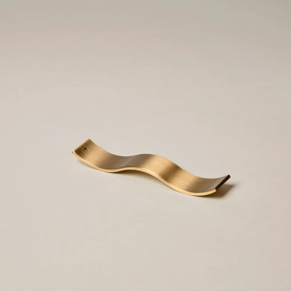 Gold wavy decorative object on a beige background