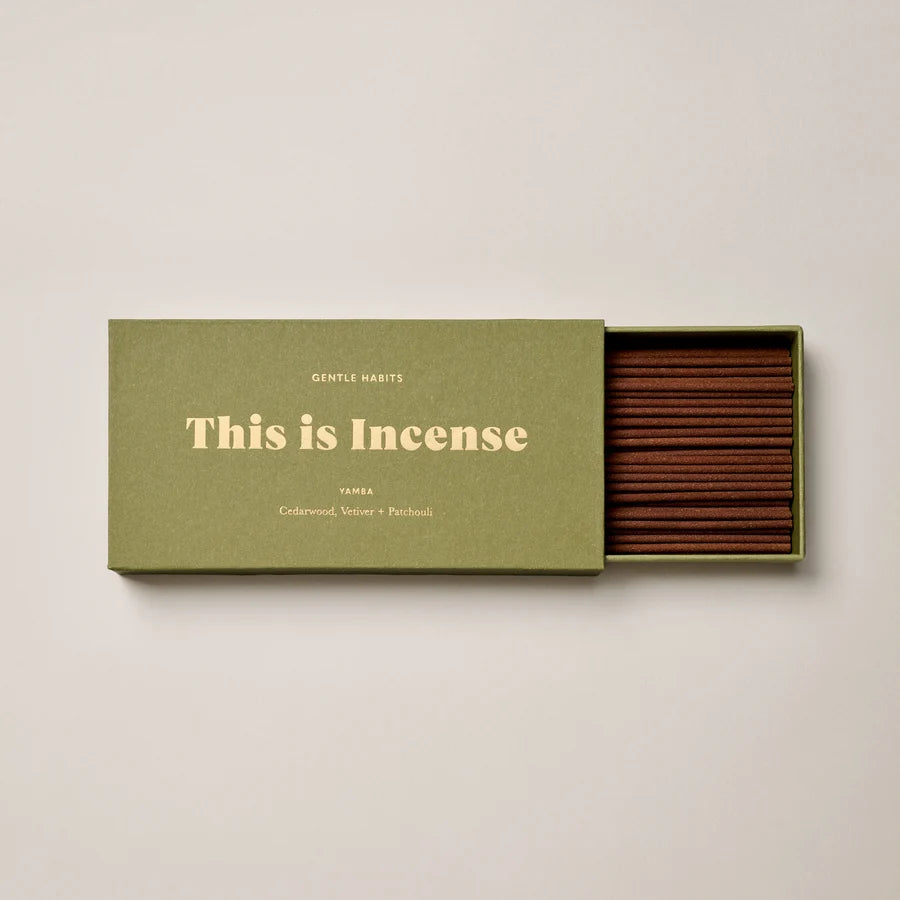 Half open small green box showcasing incense on a cream background 