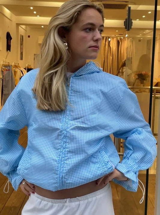 Woman wearing a blue checkered jacket in a store setting