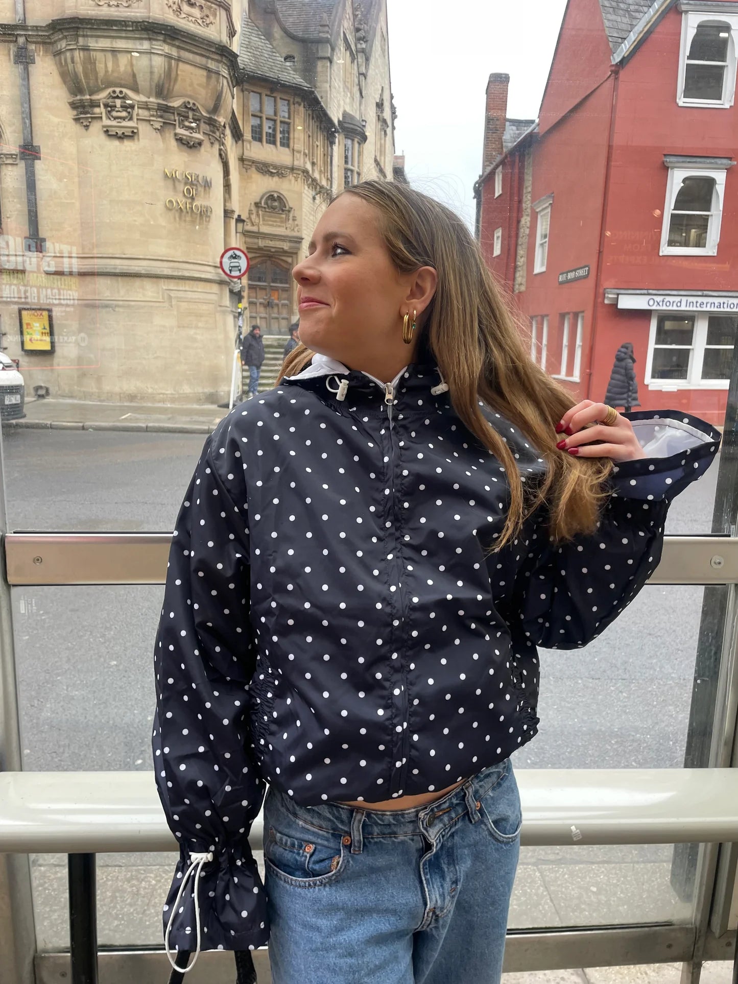 Woman wearing a navypolka dot jacket with long sleeves in an urban setting.