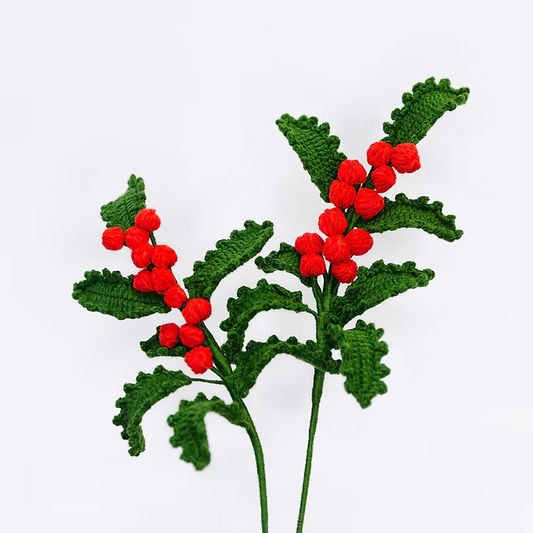 Crocheted holly leaves with red berries on a white background