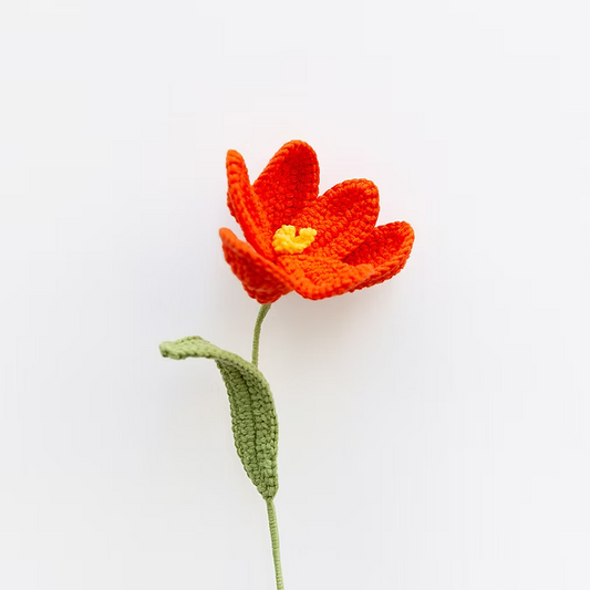 Knitted orange flower with a green stem on a white background