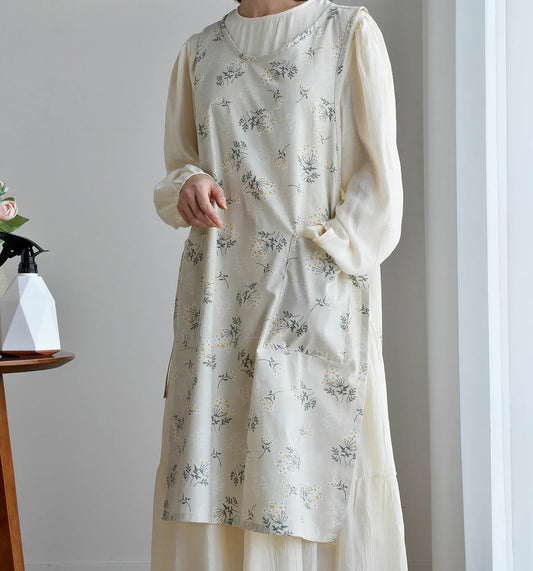 Person wearing a white floral apron in a minimal indoor setting