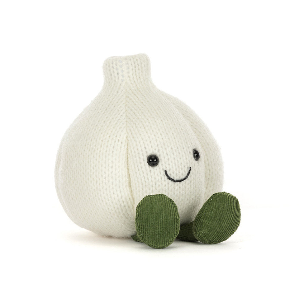 A knitted garlic plush toy in off-white with olive green feet and a simple embroidered smiley face, photographed on a clean white background.
