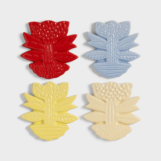 Floral shaped coasters in red, blue, yellow, and beige on a light gray background.