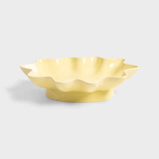 Yellow ceramic bowl with wavy edge on a light gray background