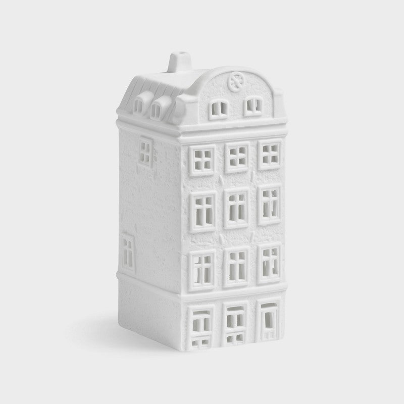 White ceramic house-shaped candle on a light gray background