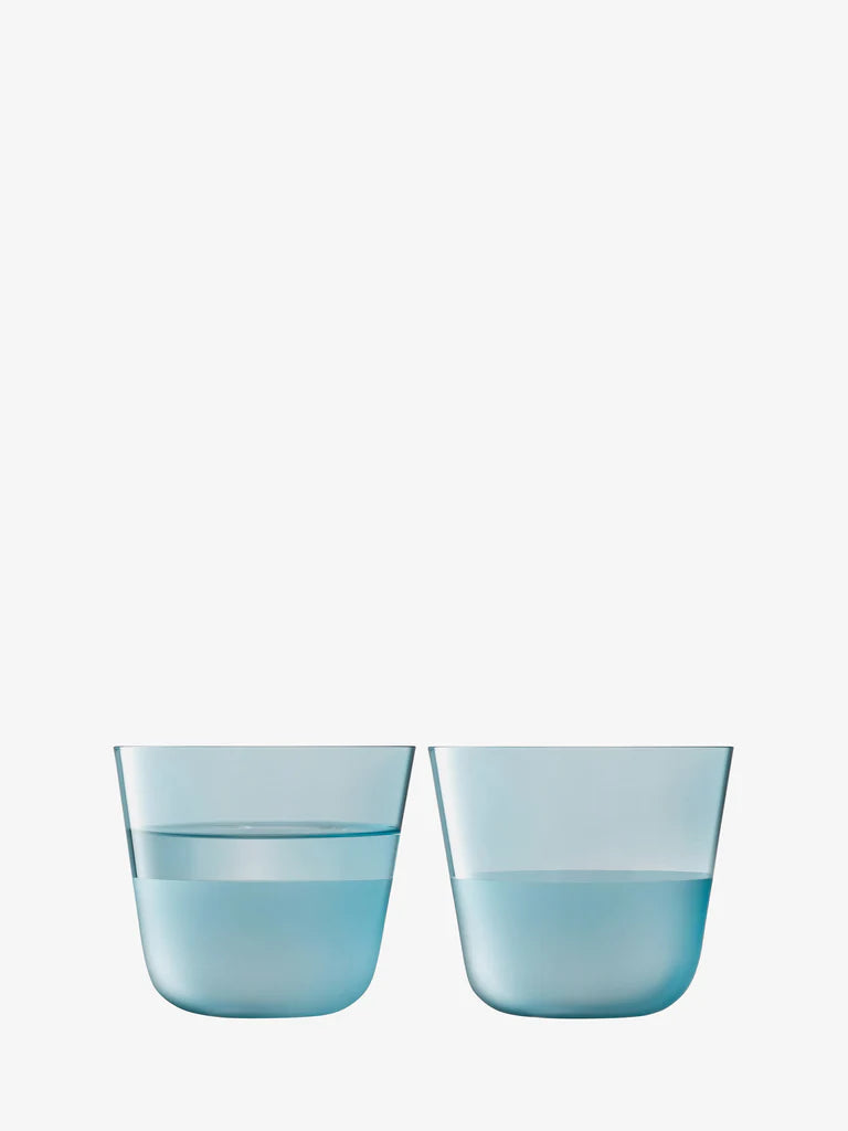 Two blue glass tumblers filled with water on a white background