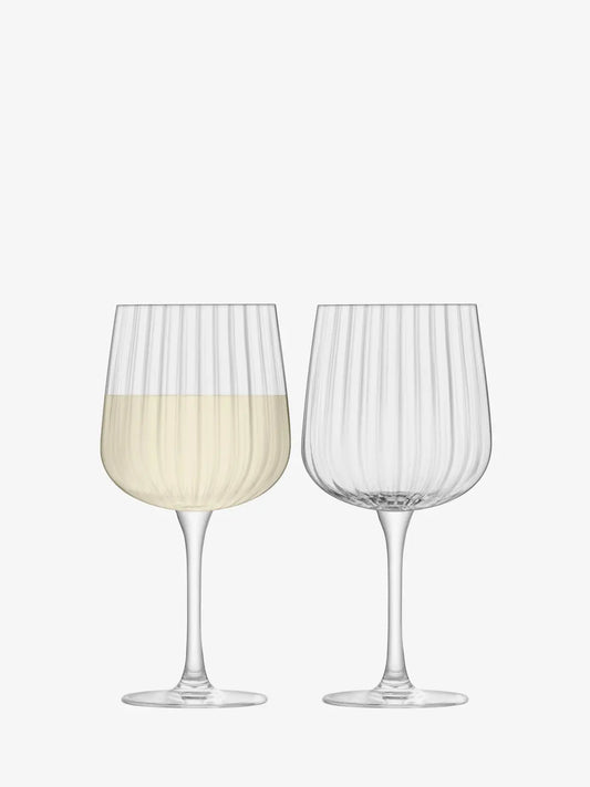 Two wine glasses with one containing a white liquid on a white background