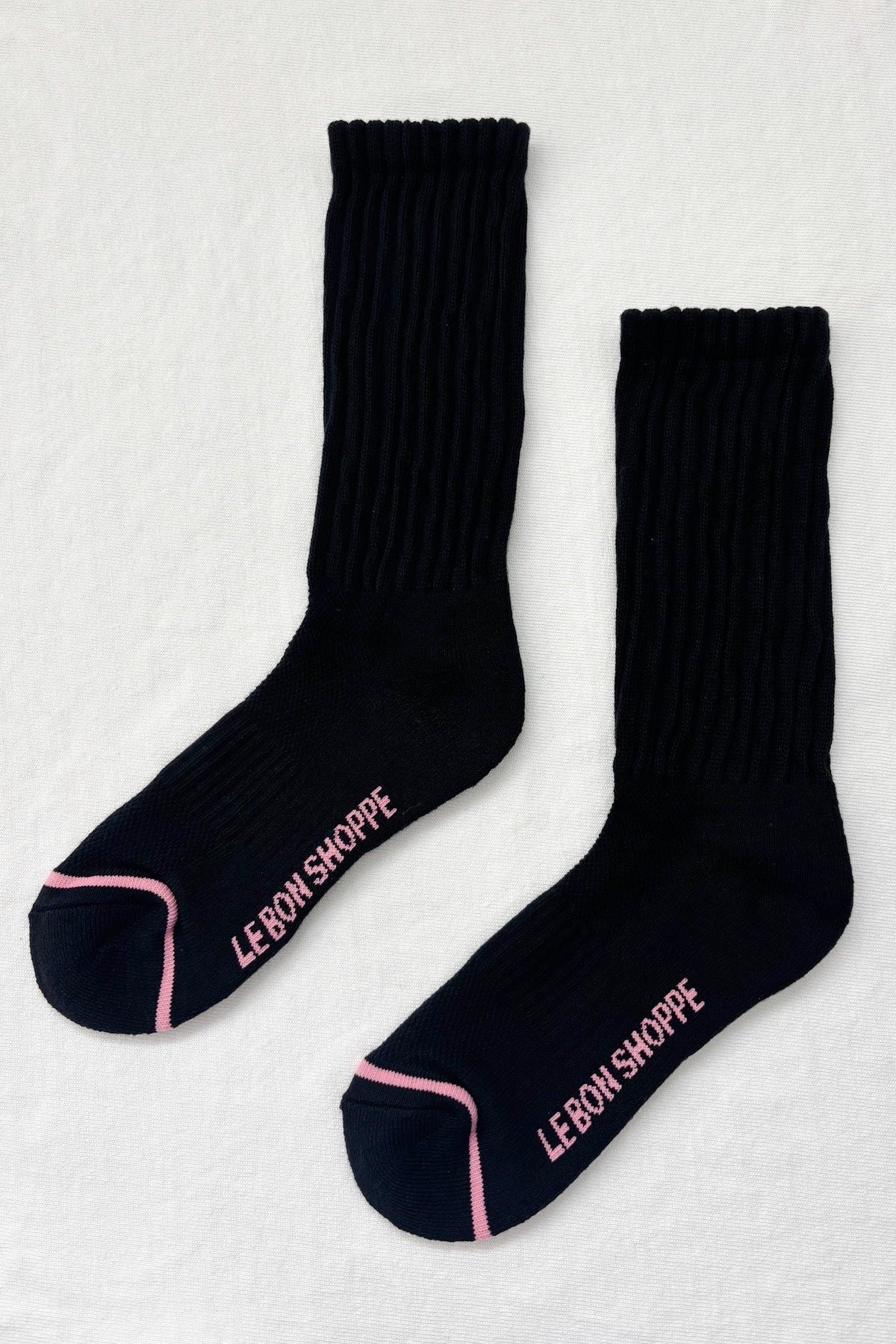 Black socks with pink trim and 'LEBON SHOPPE' branding on a light gray background