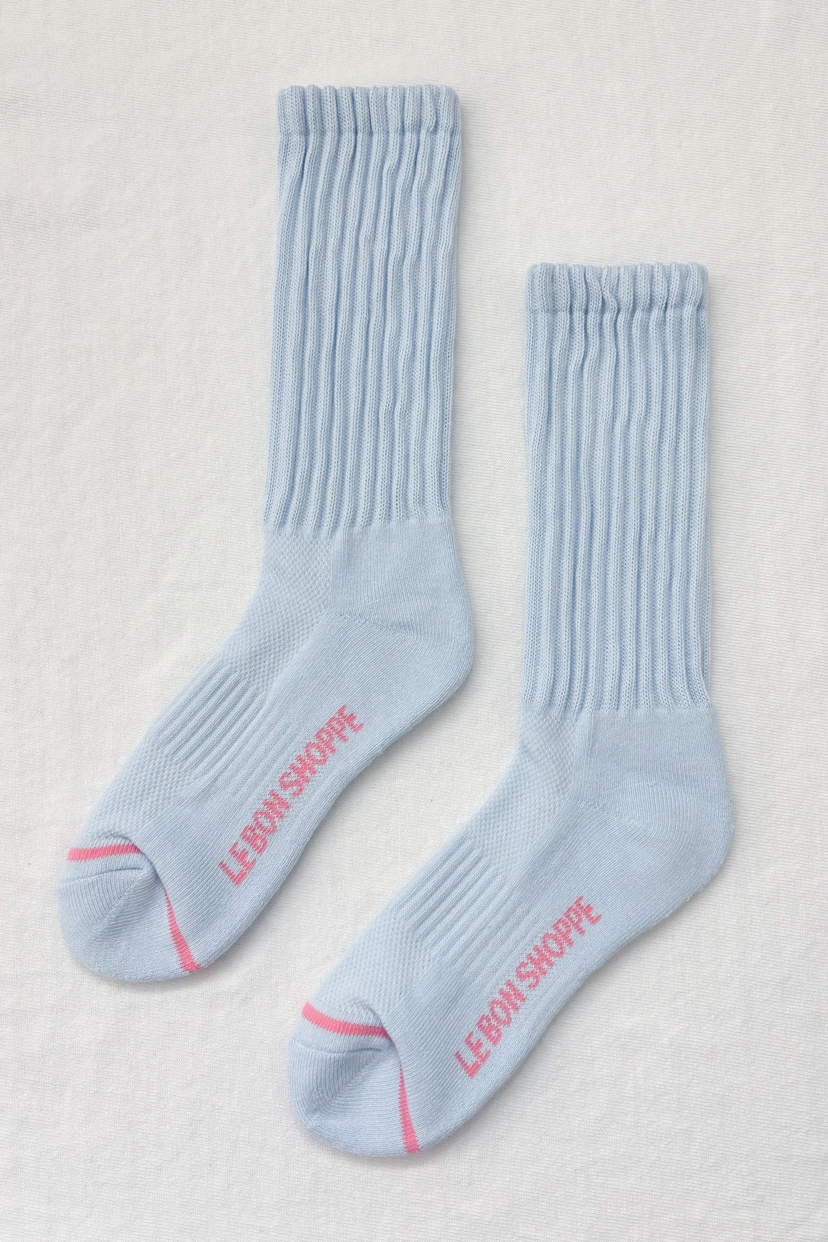 Pair of light blue socks with red text on a beige background