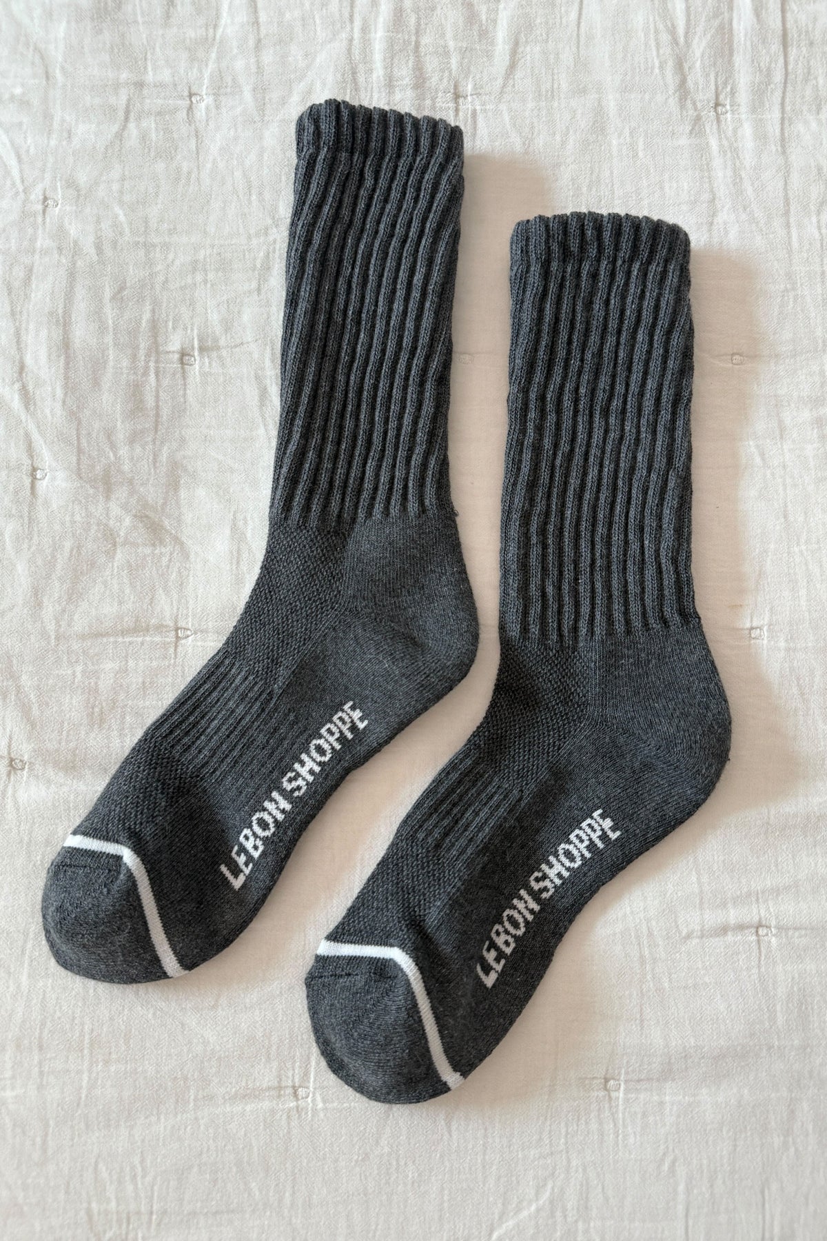 Pair of gray socks with 'Lebon Shoppe' branding on a textured surface
