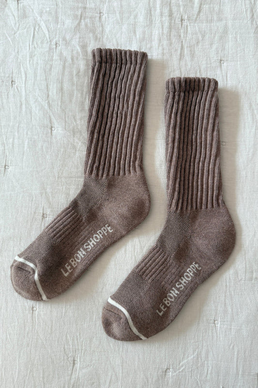 Pair of brown socks with 'Le Bon Shoppe' branding on a light wooden surface