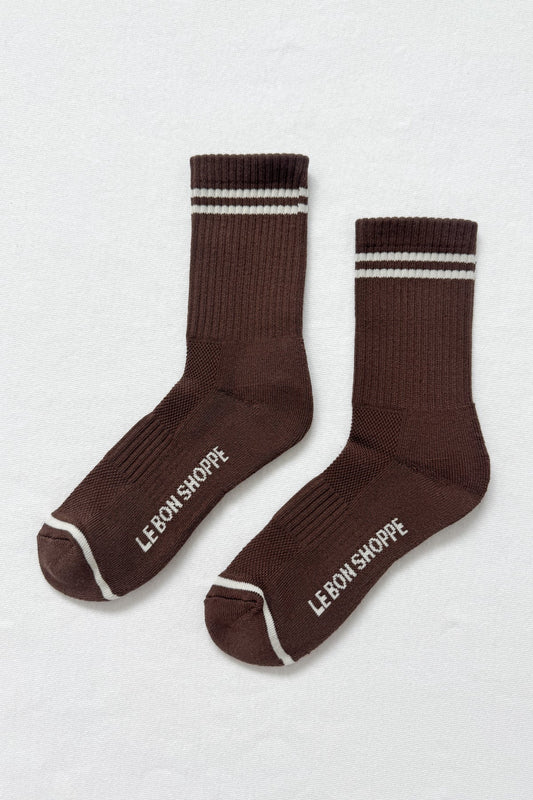 Pair of brown socks with white stripes and 'Le Bon Shoppe' branding on a light gray background