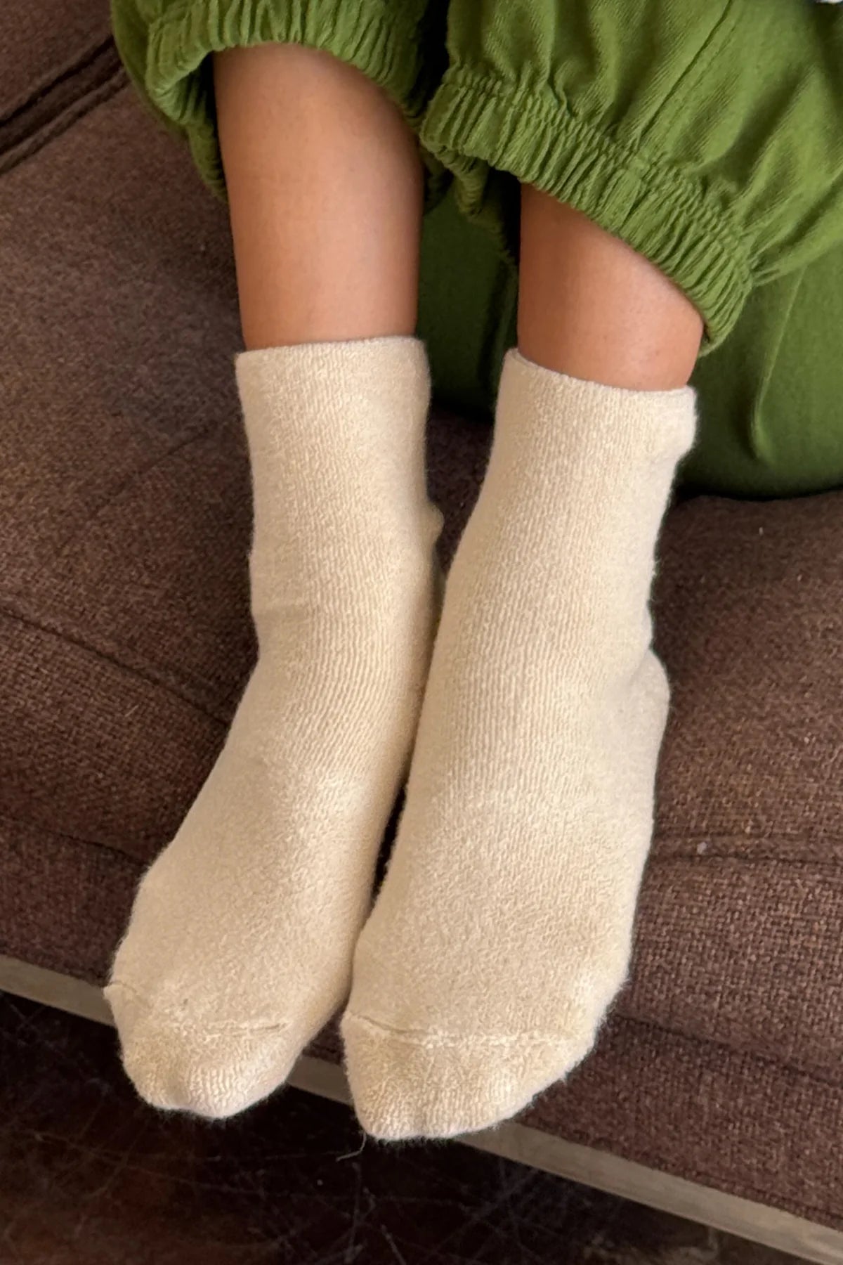 Beige socks worn with green pants on a brown surface