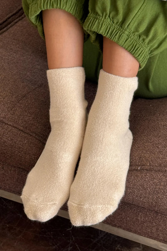 Beige socks worn with green pants on a brown surface